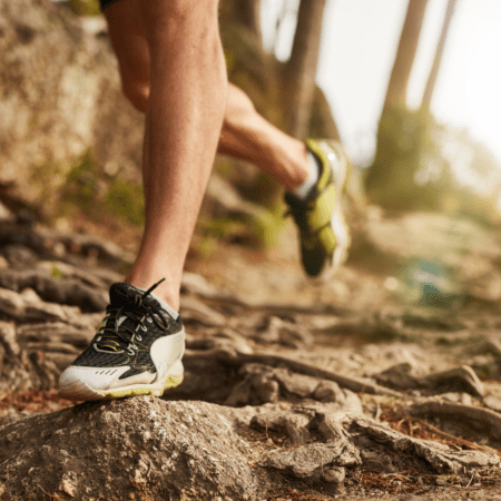Trail runner's shoes on rocky forest path