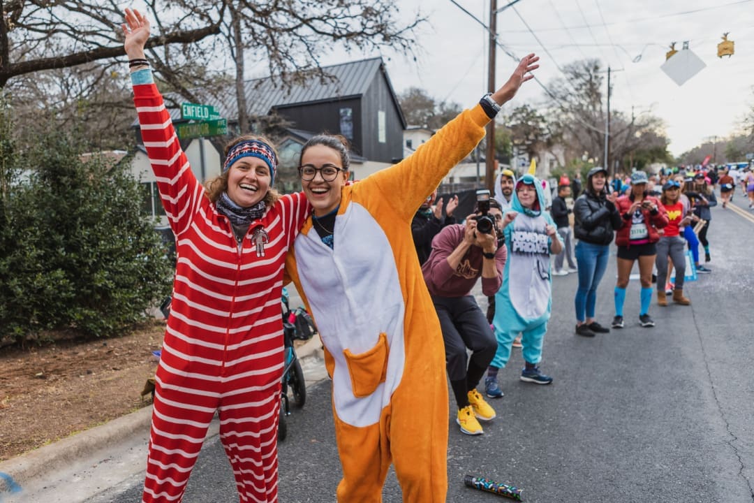 People in colorful onesies cheering at street parade