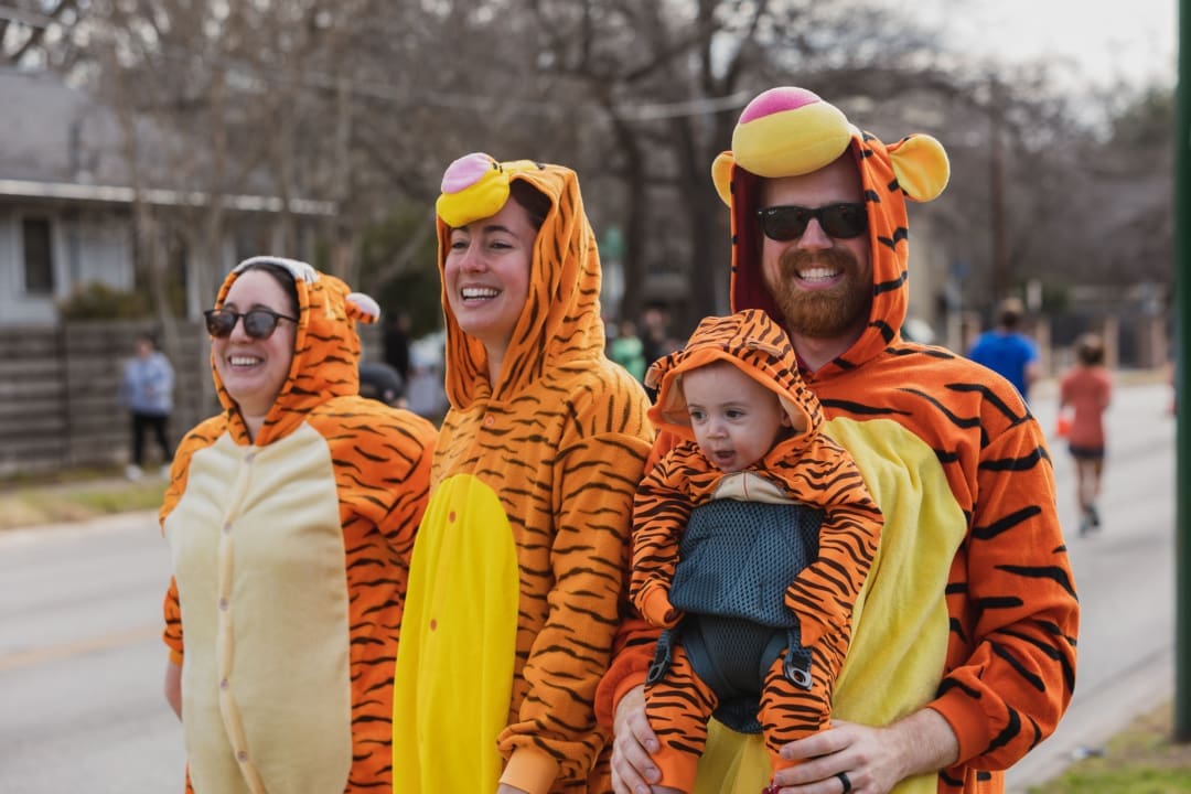 Smiling family in matching tiger onesies
