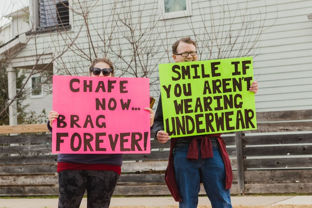 Two people holding humorous protest signs