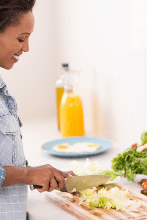 Woman chopping lettuce on cutting board in kitchen