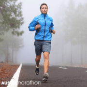 Marathon runner in blue jacket on foggy road