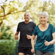 Senior couple jogging together outdoors in park