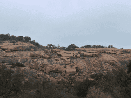 Granite cliff with scattered shrubs under overcast sky Granite cliff with scattered shrubs under overcast sky