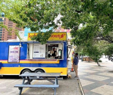 Blue and yellow food truck by picnic table Blue and yellow food truck by picnic table