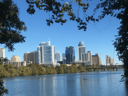 City skyline reflected across river framed by trees City skyline reflected across river framed by trees