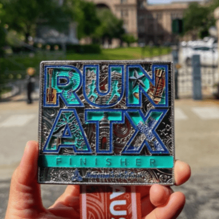 Hand holding RUN ATX finisher medal Hand holding RUN ATX finisher medal