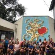 Smiling group posing before colorful heart mural Smiling group posing before colorful heart mural
