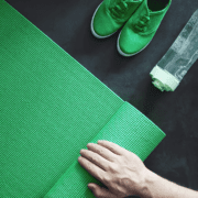 Hand rolling green yoga mat with sneakers