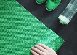 Hand rolling green yoga mat with sneakers