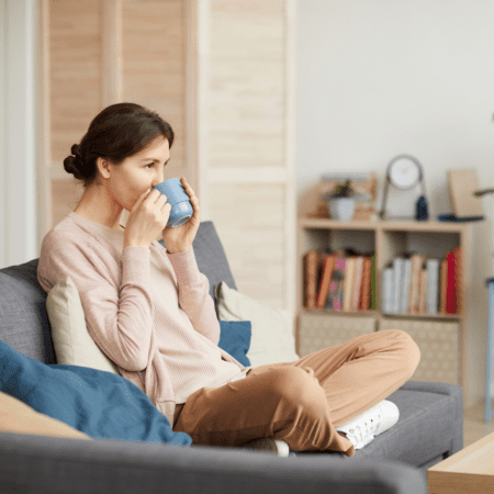 Woman relaxing on couch drinking coffee