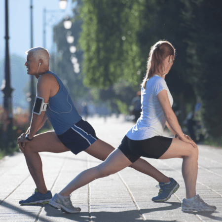 Two people stretching outdoors doing lunges