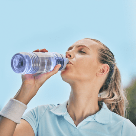 Woman drinking water from bottle outdoors