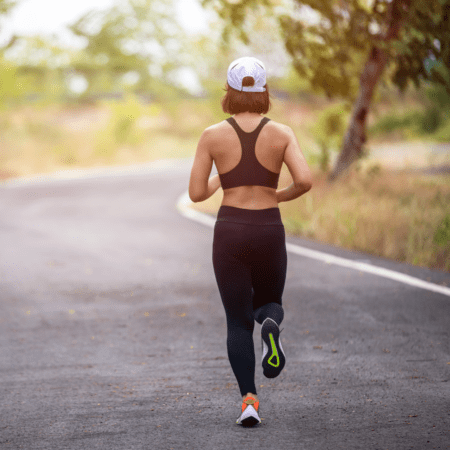Woman jogging on winding road, back view