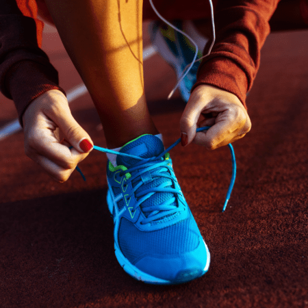 Runner tying blue sneaker laces on track Runner tying blue sneaker laces on track
