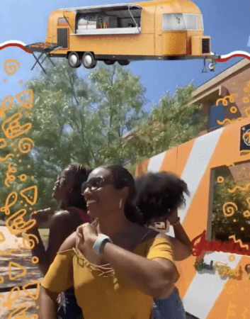 Three women laughing by striped yellow food truck