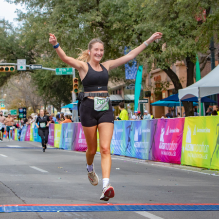 Smiling female runner crossing marathon finish line