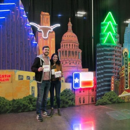 Couple holding race bibs in neon Austin backdrop Couple holding race bibs in neon Austin backdrop