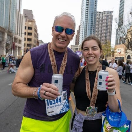 Two runners with medals holding canned drinks
