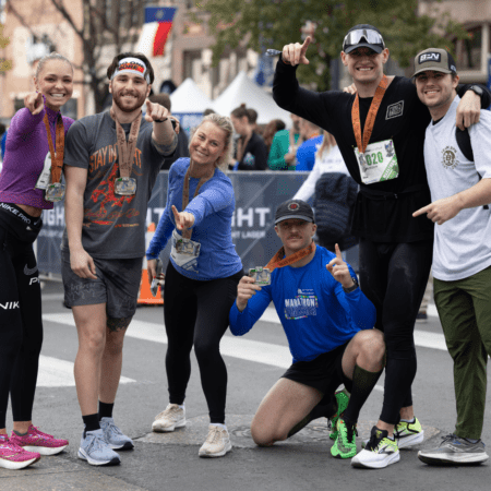 Smiling runners posing with marathon medals