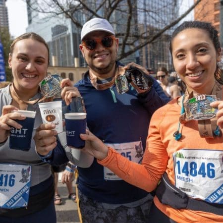 Runners smiling, holding medals and drinks