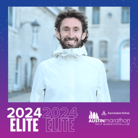 Smiling runner in white jacket with marathon banner