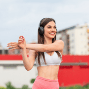Smiling woman wearing headphones stretching outdoors