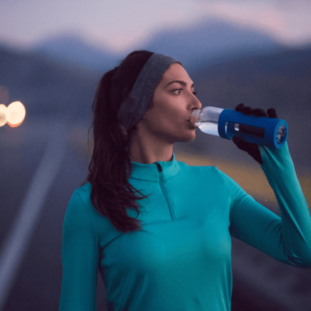 Outdoor runner drinking water from bottle