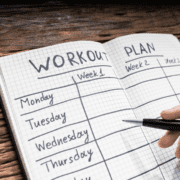 Open workout plan notebook with pen
