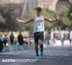 Runner finishing Austin Marathon with arms raised
