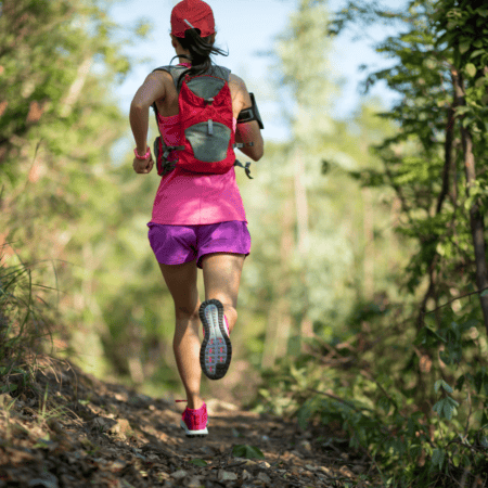 Woman trail running with red backpack