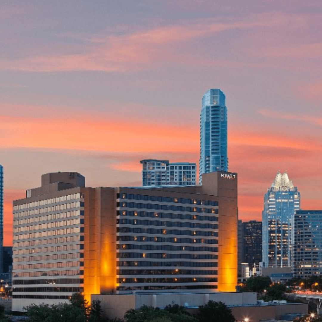 A view of a city skyline at sunset, featuring tall buildings with a prominent brown and beige hotel in the foreground. On race day, the sky is painted with warm, orange hues, adding a vibrant backdrop to the urban landscape while visitors enjoy the spectacular scenery. Austin Marathon Half Marathon & 5K A view of a city skyline at sunset, featuring tall buildings with a prominent brown and beige hotel in the foreground. On race day, the sky is painted with warm, orange hues, adding a vibrant backdrop to the urban landscape while visitors enjoy the spectacular scenery. Austin Marathon Half Marathon & 5K