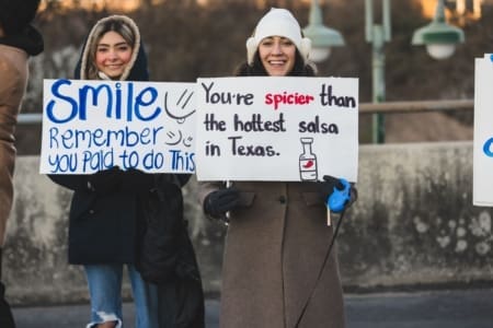 Two women holding humorous protest signs
