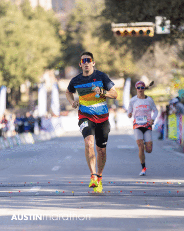 A man in a colorful striped shirt and sunglasses runs toward the finish line at the Austin Marathon race, with another runner behind him and blurred spectators in the background—captured in memorable Official Race Photos. Austin Marathon Half Marathon & 5K A man in a colorful striped shirt and sunglasses runs toward the finish line at the Austin Marathon race, with another runner behind him and blurred spectators in the background—captured in memorable Official Race Photos. Austin Marathon Half Marathon & 5K