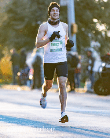 A runner in a white tank top, black shorts, gloves, and headband smiles during the Austin Marathon race. He has bib number 15922 and is outdoors with a blurred crowd in the background—perfect for your personal Official Race Photos. Austin Marathon Half Marathon & 5K A runner in a white tank top, black shorts, gloves, and headband smiles during the Austin Marathon race. He has bib number 15922 and is outdoors with a blurred crowd in the background—perfect for your personal Official Race Photos. Austin Marathon Half Marathon & 5K