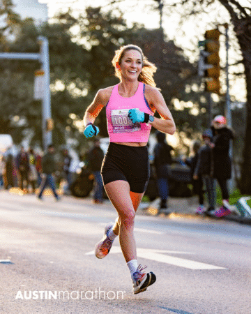 A female runner in a pink top and black shorts smiles while racing in the Austin Marathon, sunlight and spectators behind her. The event logo "AUSTINmarathon" is visible on the street—perfect for your Official Race Photos collection. Austin Marathon Half Marathon & 5K A female runner in a pink top and black shorts smiles while racing in the Austin Marathon, sunlight and spectators behind her. The event logo "AUSTINmarathon" is visible on the street—perfect for your Official Race Photos collection. Austin Marathon Half Marathon & 5K