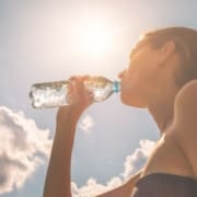 Person drinking water from bottle in sunlight