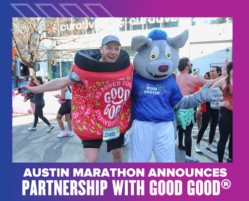 Two people at the Austin Marathon: one is dressed as a jar of GOOD GOOD strawberry jam, the other as a wolf mascot in an “Austin Marathon” shirt. Both are smiling with arms outstretched, celebrating the Ascension Seton partnership announcement. Austin Marathon Half Marathon & 5K