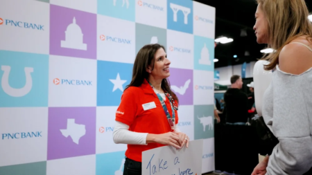 A woman in a red shirt holds a sign and chats with another woman at the Austin Marathon Expo. Behind her, a PNC Bank display with pastel squares stands out as attendees explore the expo and check out running gear. Austin Marathon Half Marathon & 5K A woman in a red shirt holds a sign and chats with another woman at the Austin Marathon Expo. Behind her, a PNC Bank display with pastel squares stands out as attendees explore the expo and check out running gear. Austin Marathon Half Marathon & 5K
