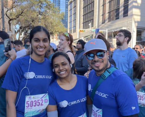 Three runners in blue shirts smiling at race