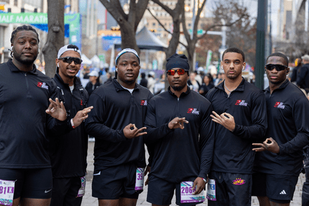 Six men in matching black athletic wear pose together outdoors at a marathon event, each making hand signs, showing off their race bibs—a perfect example of social teams coming together through training, with city buildings in the background. Austin Marathon Half Marathon & 5K Six men in matching black athletic wear pose together outdoors at a marathon event, each making hand signs, showing off their race bibs—a perfect example of social teams coming together through training, with city buildings in the background. Austin Marathon Half Marathon & 5K
