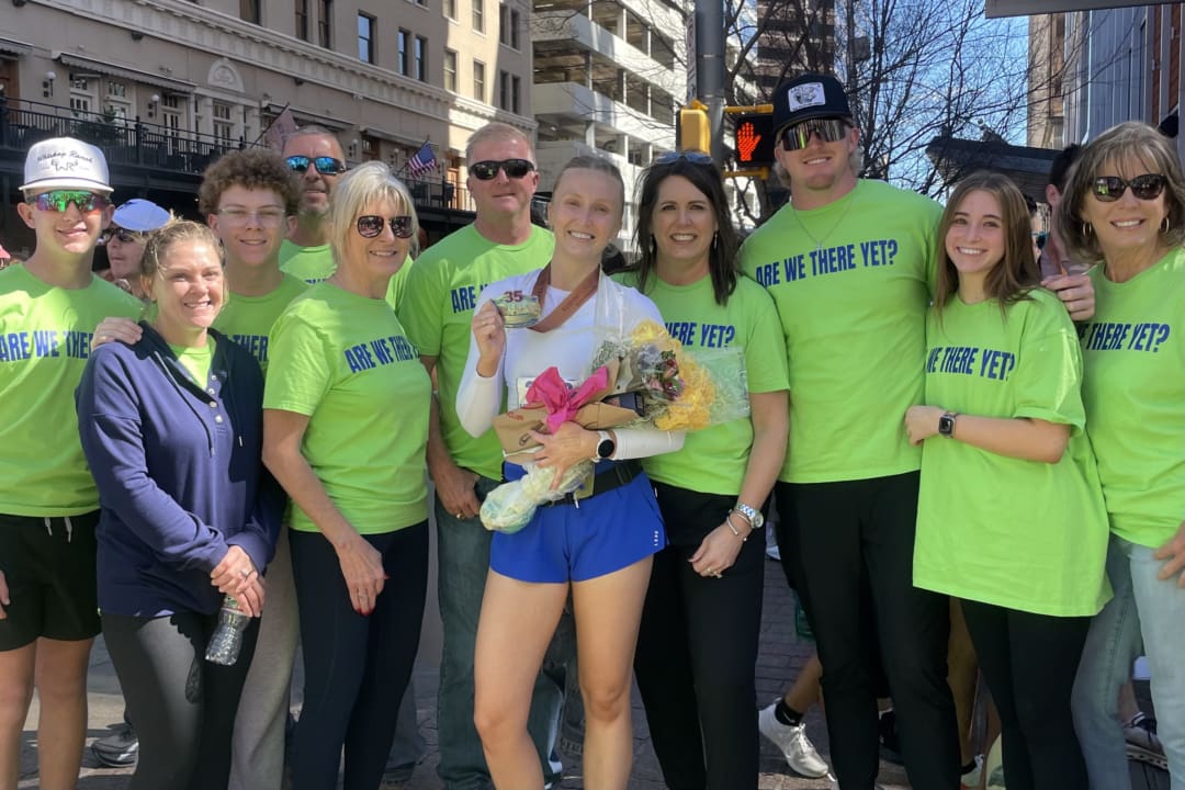 Marathon winner holding bouquet surrounded by supporters Marathon winner holding bouquet surrounded by supporters