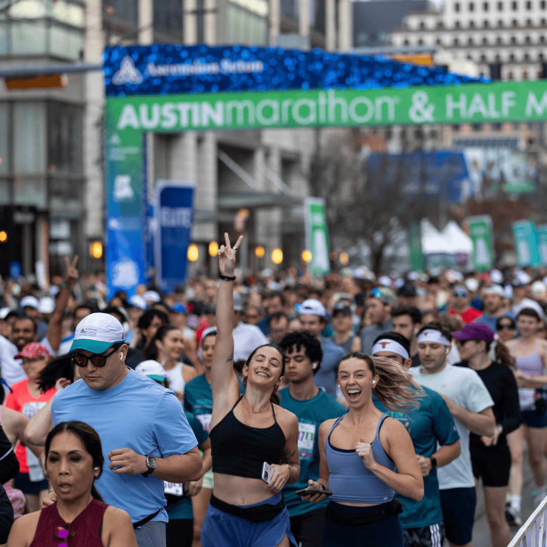 A large group of runners participates in the Ascension Seton Austin Marathon & Half Marathon. Two women at the front smile and gesture enthusiastically, while others follow behind under the event’s green and blue banner. Austin Marathon Half Marathon & 5K A large group of runners participates in the Ascension Seton Austin Marathon & Half Marathon. Two women at the front smile and gesture enthusiastically, while others follow behind under the event’s green and blue banner. Austin Marathon Half Marathon & 5K