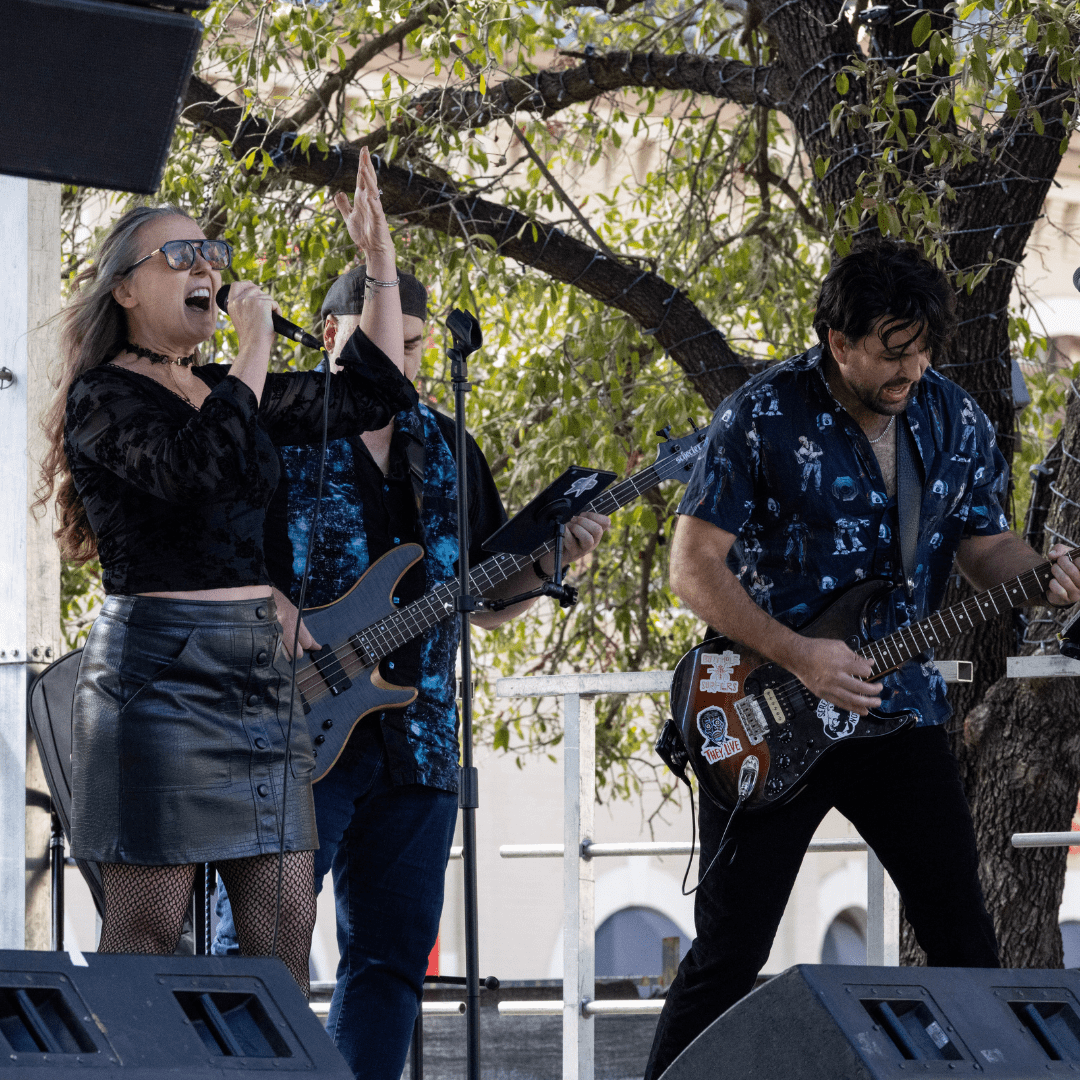A woman passionately sings into a microphone while two men play electric guitar and bass on an outdoor stage, as leafy trees and lights set the scene—capturing the vibrant energy that echoes throughout Austin Marathon history. Austin Marathon Half Marathon & 5K A woman passionately sings into a microphone while two men play electric guitar and bass on an outdoor stage, as leafy trees and lights set the scene—capturing the vibrant energy that echoes throughout Austin Marathon history. Austin Marathon Half Marathon & 5K