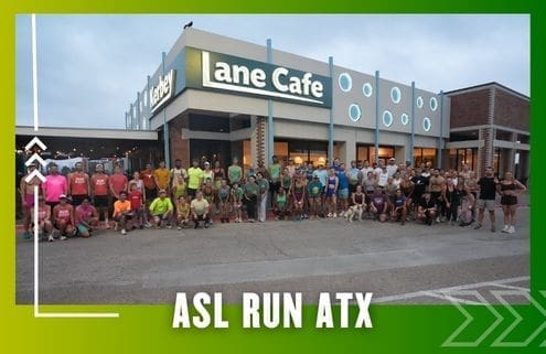 A large group of people pose outside Lane Cafe at dawn or dusk in athletic clothes, representing a Group Run. Text at the bottom reads "ASL RUN ATX." The image features a green and yellow border with arrow graphics. Austin Marathon Half Marathon & 5K