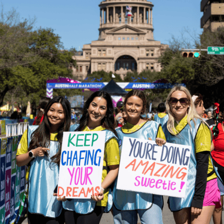 Smiling volunteers with motivational signs at Austin marathon