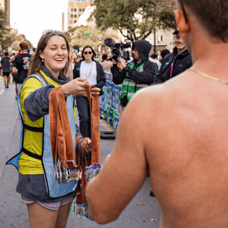 Race volunteer handing medals to runner