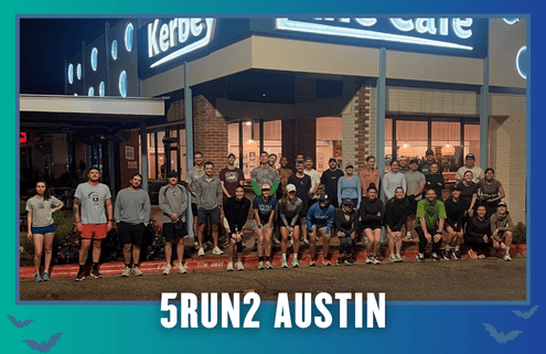 About 30 people stand in front of a café at night, gathered for a group photo during KickOff Week. The text “5RUN2 AUSTIN” is at the bottom. The café sign and running attire suggest this is a group run with Cafecito Run Club, highlighting their strong sense of community. Austin Marathon Half Marathon & 5K