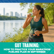 A woman in athletic gear eats an energy gel while running on a riverside trail with a city skyline in the background. Text reads: “Gut Training: How to Practice Your Marathon Fueling Plan in September.” This scene highlights the importance of marathon fueling and gut training as essential parts of marathon training. Austin Marathon Half Marathon & 5K