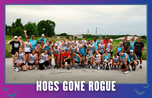 A large group of runners in athletic gear pose together outdoors on a road in South Austin, smiling and celebrating. Text reads “HOGS GONE ROGUE” in bold letters at the bottom of the image, capturing the excitement of this group run during KickOff Week. Austin Marathon Half Marathon & 5K